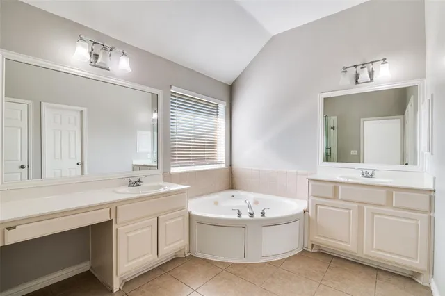 a bathroom with a tub double sink window and mirror