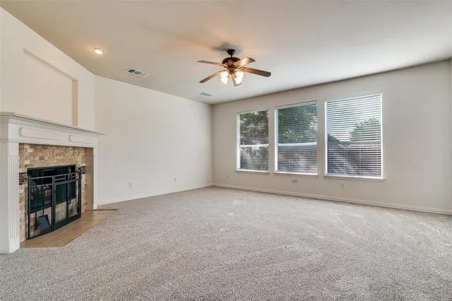 a view of an empty room with chandelier fan and fire place