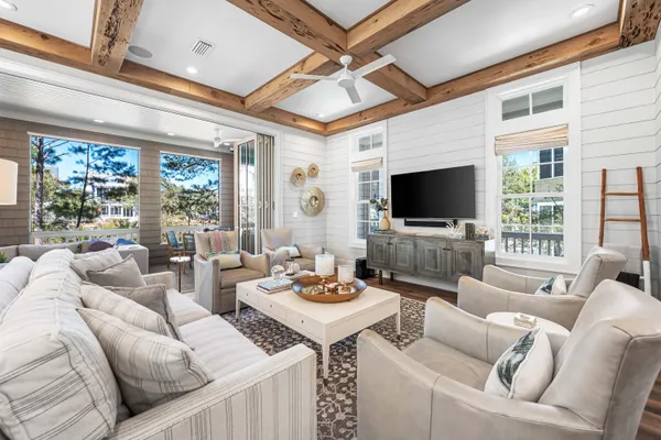 a living room with furniture a flat screen tv and a floor to ceiling window