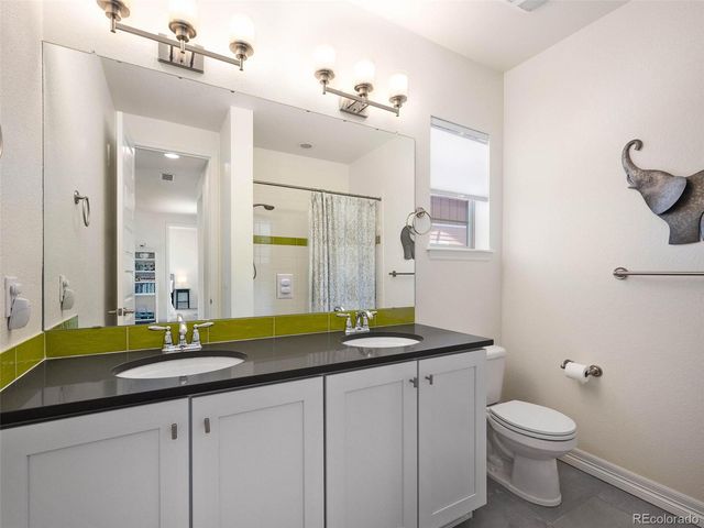 a bathroom with a granite countertop sink a toilet and a mirror