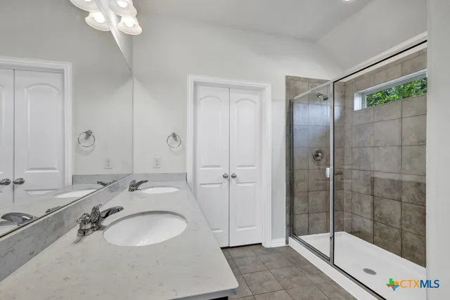 a bathroom with a granite countertop sink a mirror and a shower