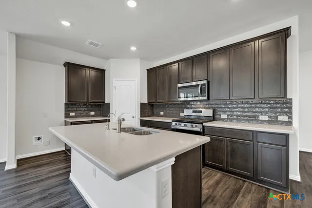 a kitchen with kitchen island a sink stove and microwave
