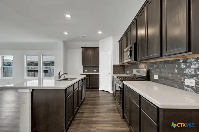 a kitchen with stainless steel appliances granite countertop a sink a stove and a refrigerator