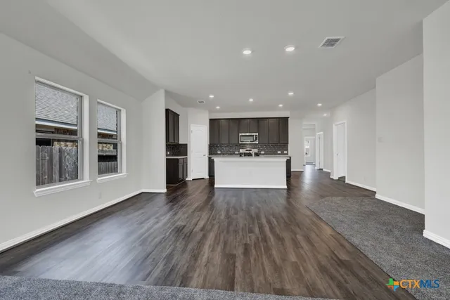 a view of a livingroom with wooden floor and kitchen