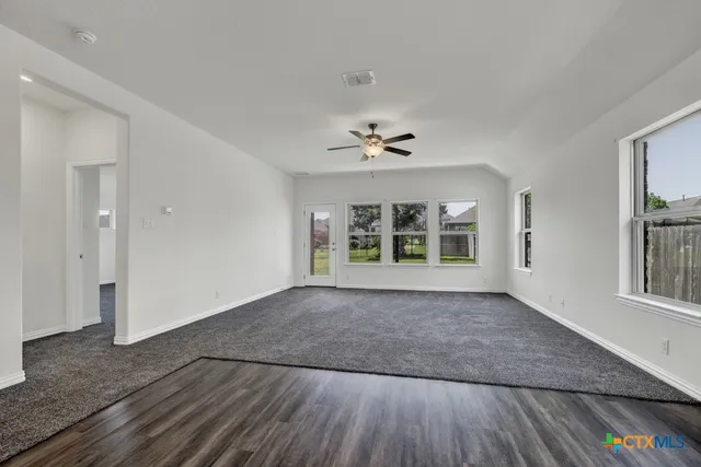 a view of an empty room with a window and wooden floor