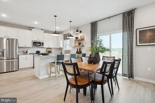 a kitchen with kitchen island a dining table chairs stainless steel appliances and cabinets
