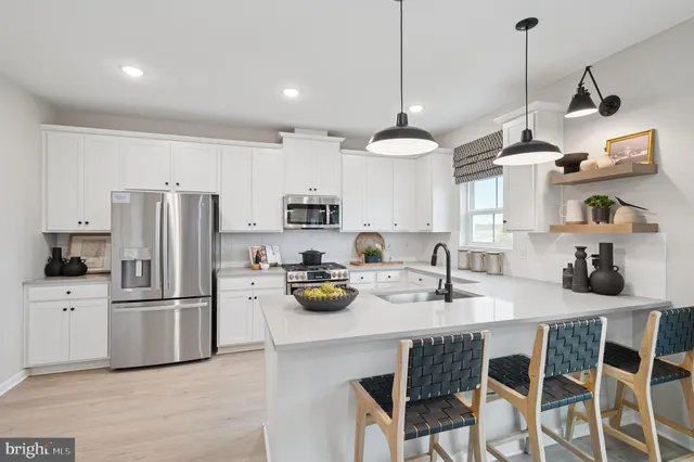 a kitchen with a refrigerator a stove a sink and chairs