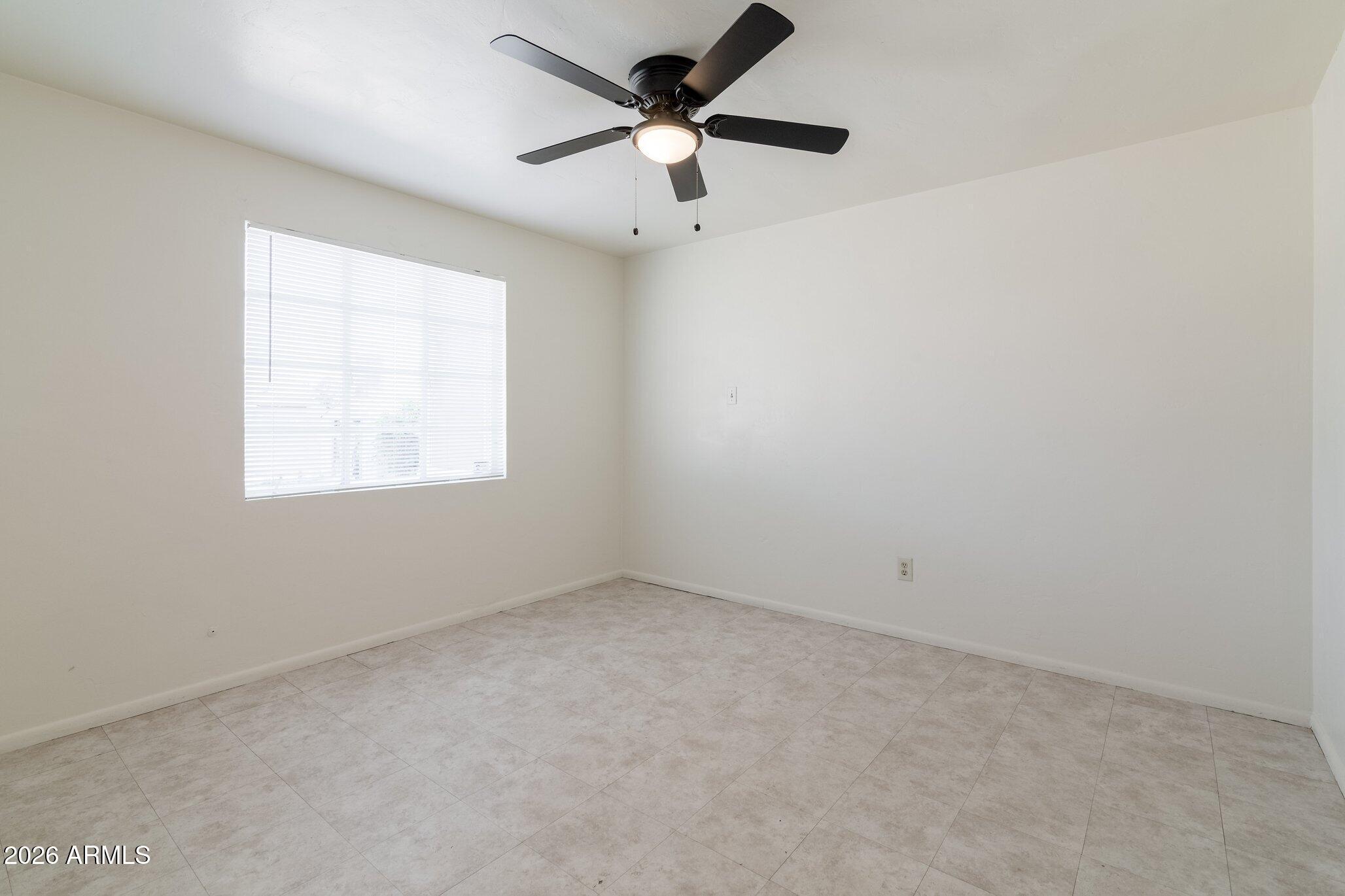 1335 East Broadway Road Mesa, AZ 85204 - Photo 12 of 23 an empty room with a window and a fan