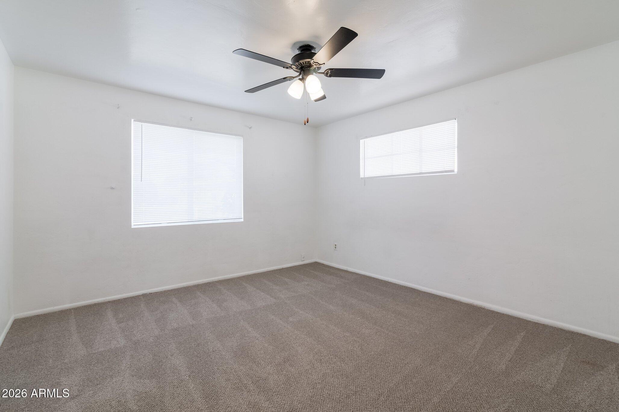 1335 East Broadway Road Mesa, AZ 85204 - Photo 15 of 23 an empty room with a window and a ceiling fan