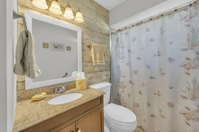 a bathroom with a granite countertop sink a toilet and a mirror