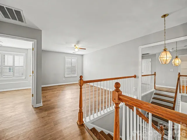 a view of a hallway with wooden floor and stairs