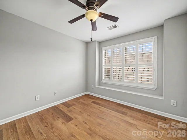 a view of an empty room with window and a chandelier fan