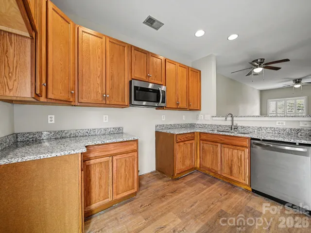 a kitchen with stainless steel appliances granite countertop wooden cabinets a sink and a granite counter tops