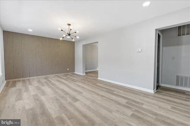 wooden floor in an empty room with a chandelier