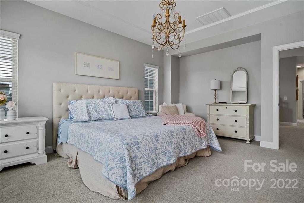 221 Helton Lane Fort Mill, SC 29708 - Photo 29 of 48 a spacious bedroom with a bed and a chandelier