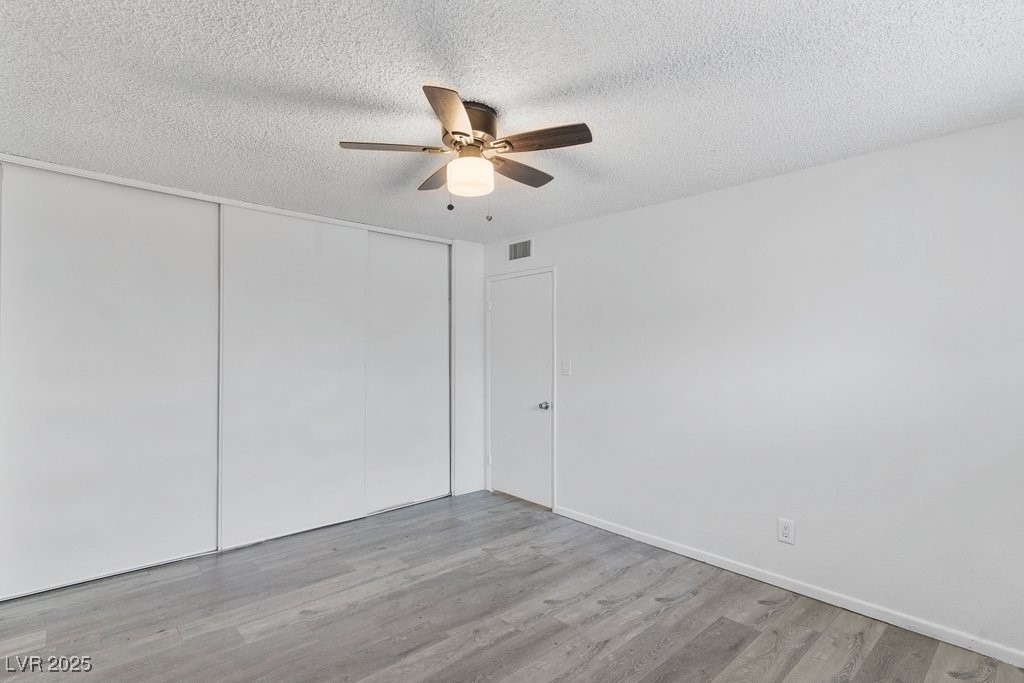 350 East Desert Inn Road, Unit H205 Las Vegas, NV 89109 - Photo 11 of 30 Unfurnished bedroom with a textured ceiling, wood finished floors, a closet, and a ceiling fan