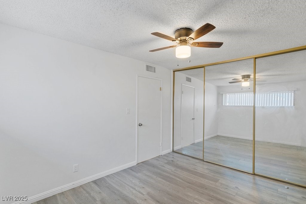 350 East Desert Inn Road, Unit H205 Las Vegas, NV 89109 - Photo 14 of 30 Unfurnished bedroom featuring a textured ceiling, wood finished floors, ceiling fan, and a closet
