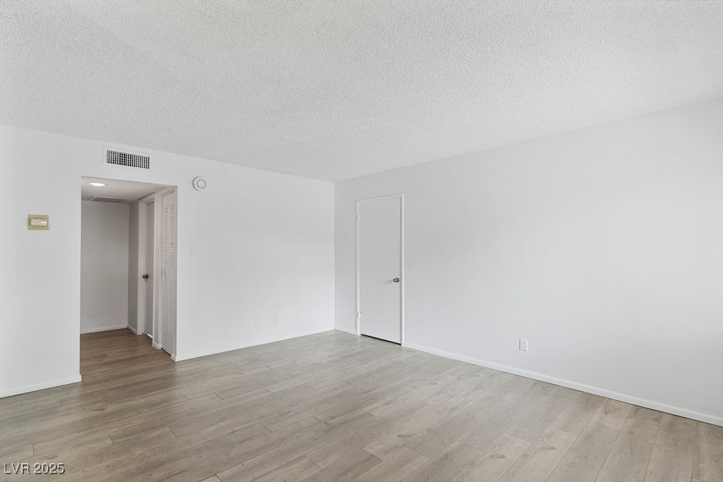 350 East Desert Inn Road, Unit H205 Las Vegas, NV 89109 - Photo 15 of 30 Unfurnished room featuring wood finished floors and a textured ceiling