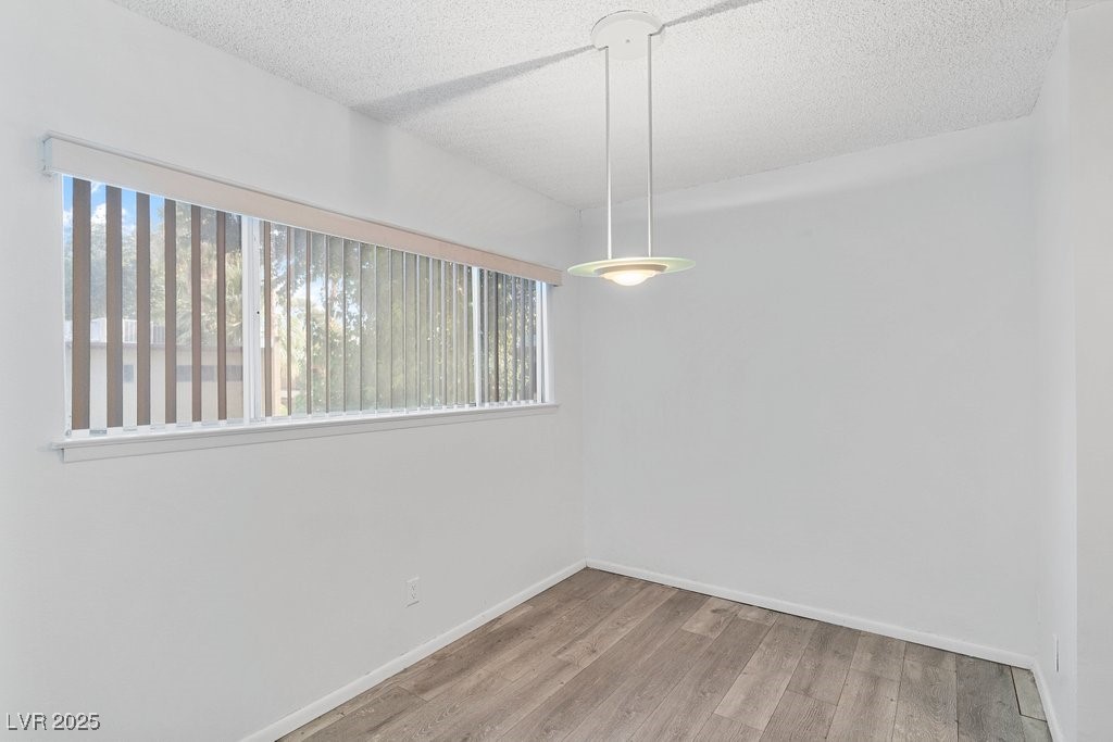 350 East Desert Inn Road, Unit H205 Las Vegas, NV 89109 - Photo 18 of 30 Empty room featuring wood finished floors and a textured ceiling