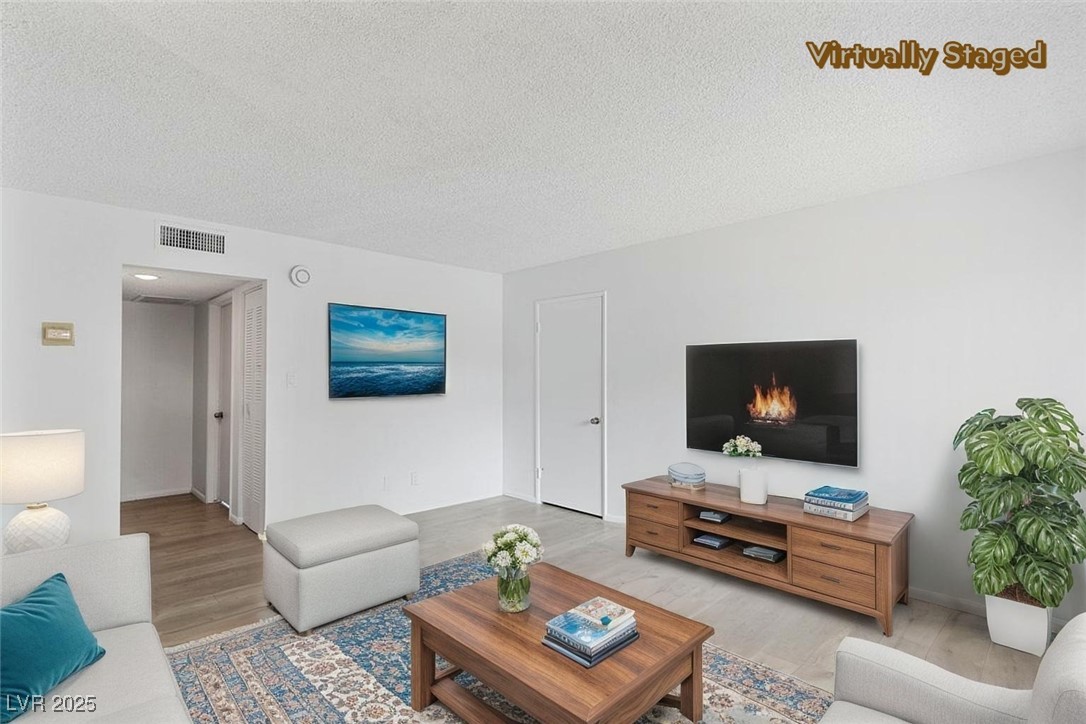 350 East Desert Inn Road, Unit H205 Las Vegas, NV 89109 - Photo 2 of 30 Living area featuring wood finished floors and a textured ceiling