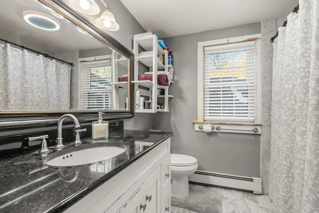a bathroom with a granite countertop sink mirror vanity and a toilet
