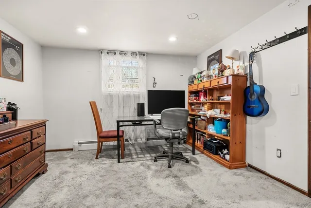 a work room with furniture a rug and a window