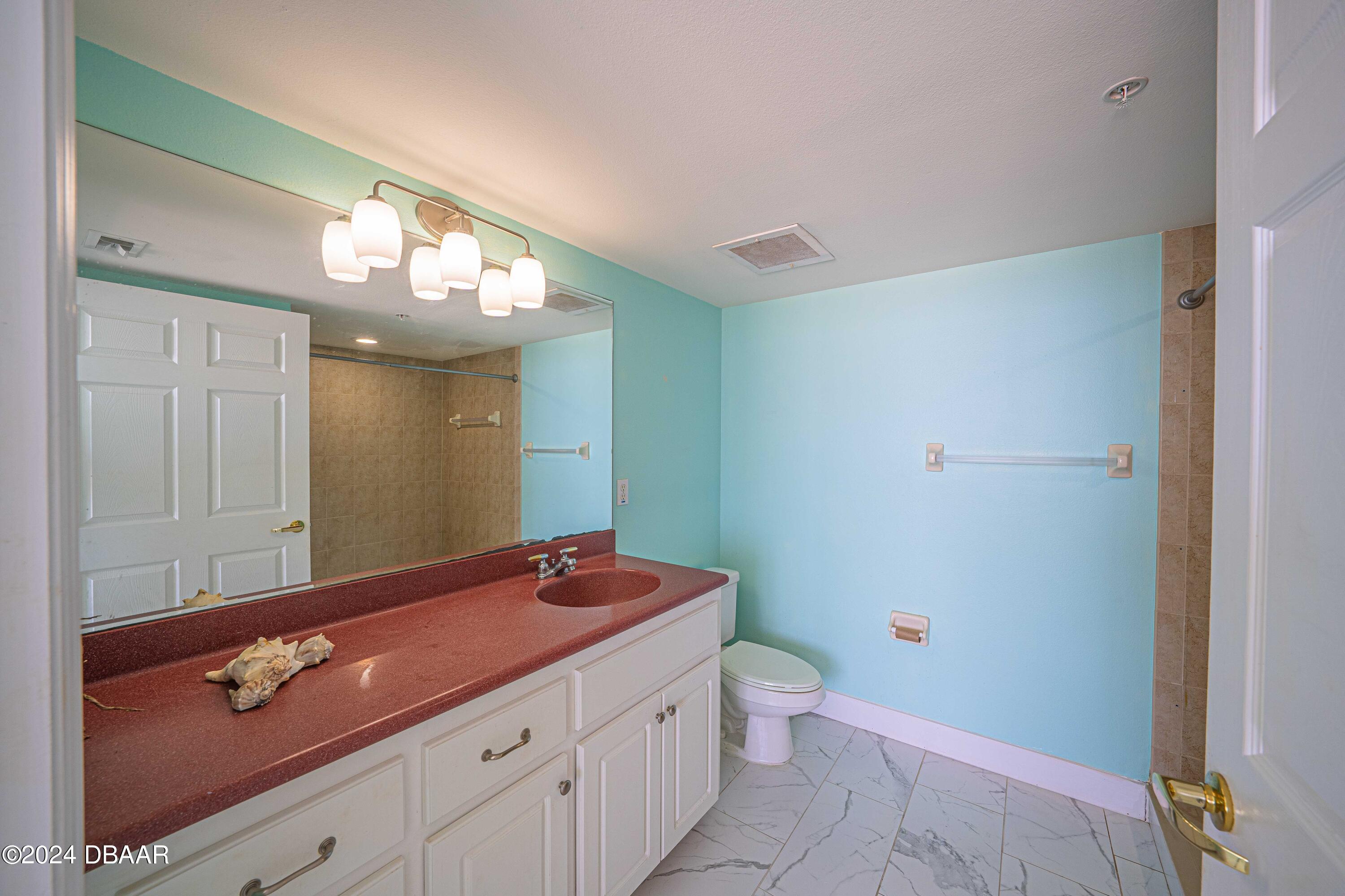 4767 South Atlantic Avenue, Unit 204 Ponce Inlet, FL 32127 - Photo 11 of 26 a bathroom with a sink a toilet and a mirror