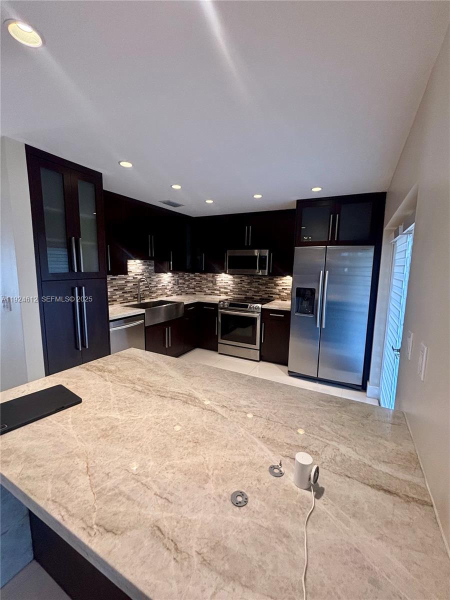 13765 Southwest 160th Terrace Miami, FL 33177 - Photo 14 of 47 a kitchen with stainless steel appliances kitchen island granite countertop a refrigerator stove a sink dishwasher and wooden cabinets