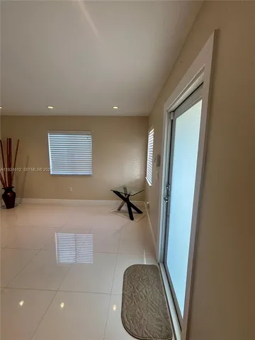 a hallway with a couch and a potted plant next to a window