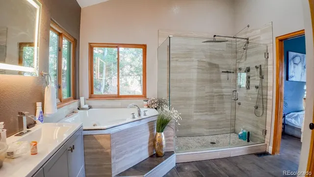 a bathroom with a tub shower sink and mirror