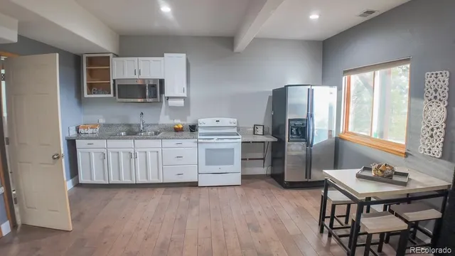 a kitchen with stainless steel appliances a stove a sink dishwasher a refrigerator with a dining table and chairs