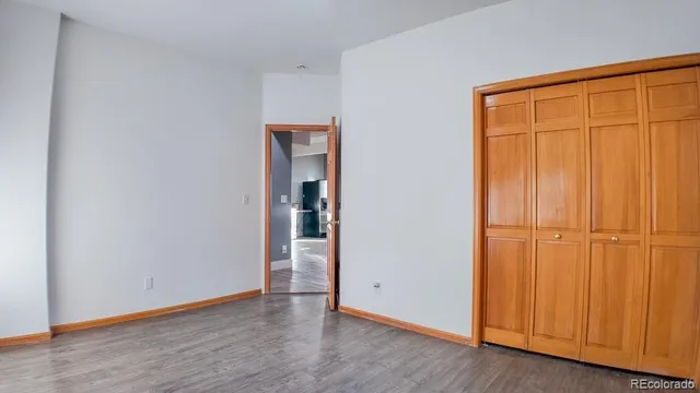 an empty room with wooden floor and closet area