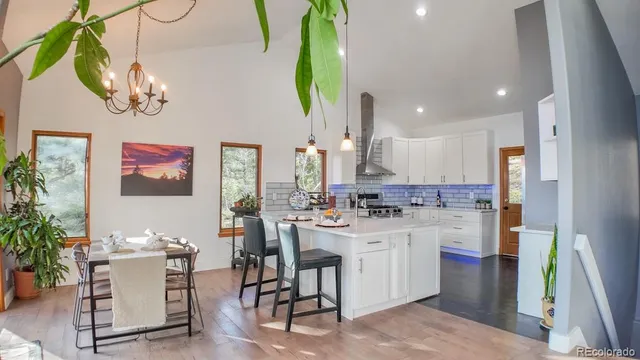 a kitchen with a sink dishwasher a stove a dining table and chairs with wooden floor