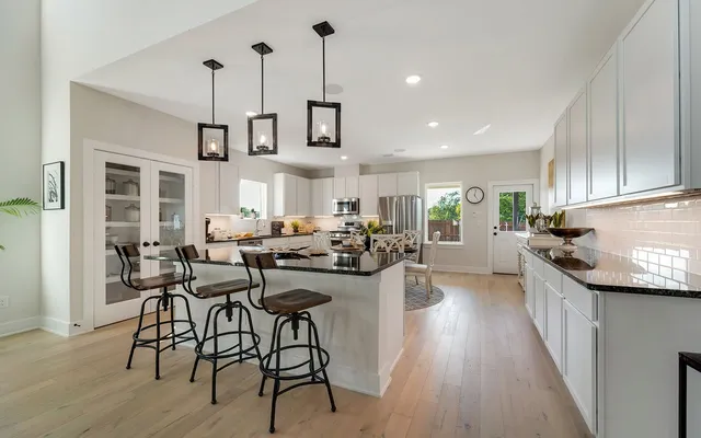 a kitchen with stainless steel appliances kitchen island granite countertop a table chairs stove and white cabinets