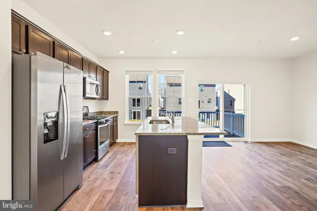 a kitchen with stainless steel appliances granite countertop a refrigerator a stove and a sink