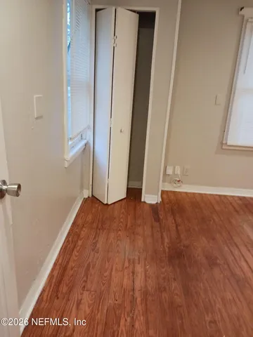 an empty room with wooden floor and entrance