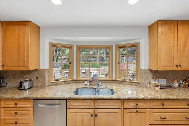 a kitchen with granite countertop a sink window and cabinets