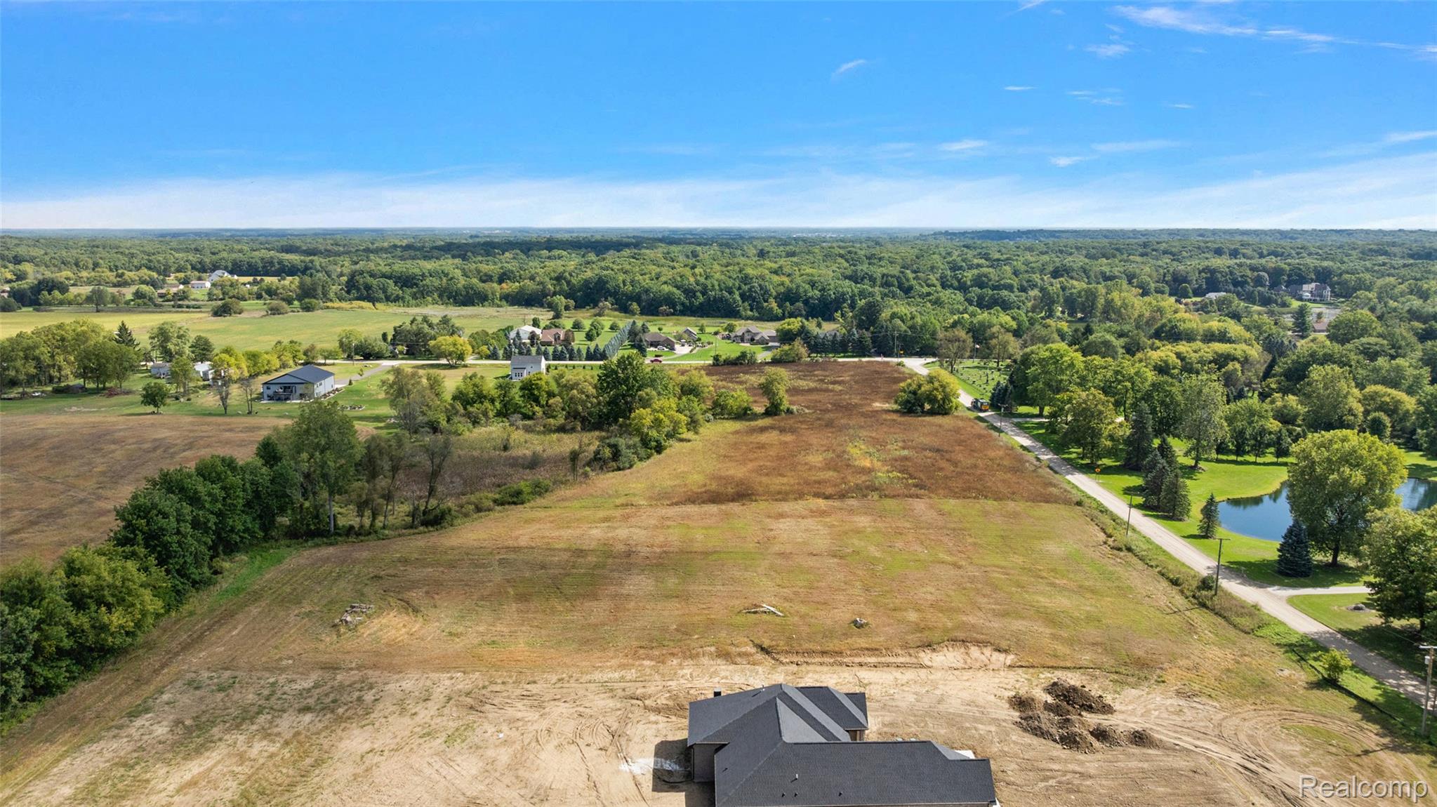 4059 Taft Road Romeo, MI 48065 - Photo 13 of 59 Expansive open land with mature tree lines, a tranquil pond, and a partially constructed property