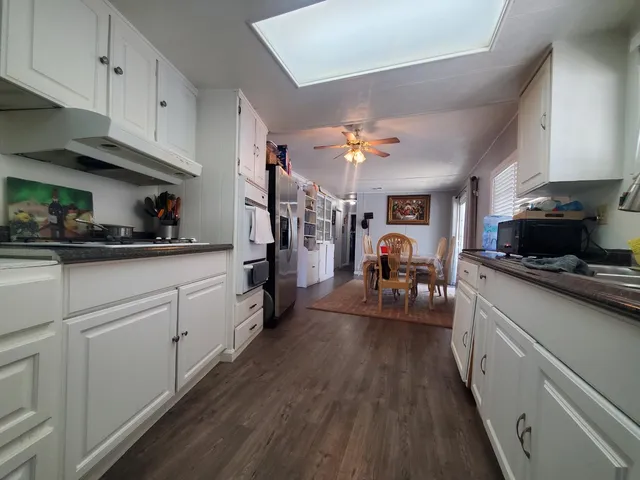 a kitchen with a sink dishwasher a stove and white cabinets with wooden floor