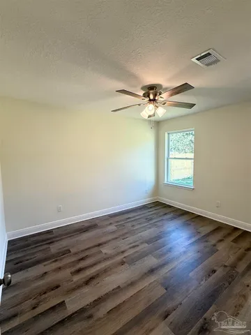 an empty room with wooden floor chandelier fan and windows