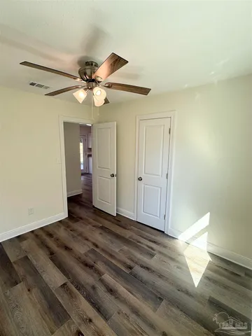 a view of a livingroom with a chandelier fan and wooden floor