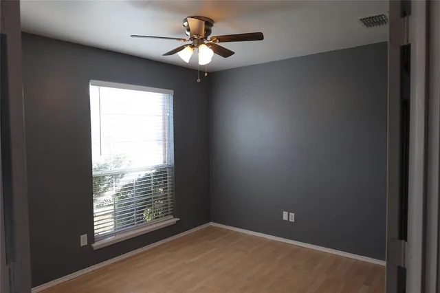 an empty room with windows and fan