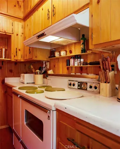 a utility room with stainless steel appliances wooden floor a stove and a refrigerator