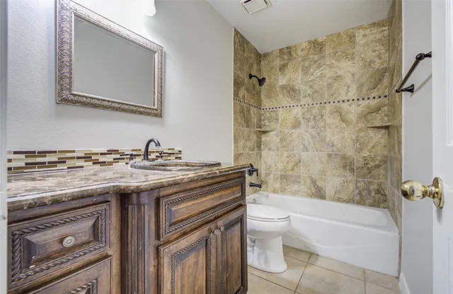 a bathroom with a granite countertop sink a toilet and shower