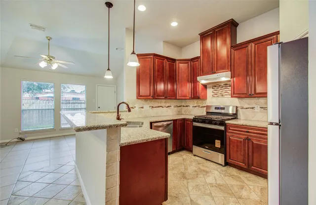 a kitchen with stainless steel appliances granite countertop wooden cabinets a stove top oven a sink and dishwasher