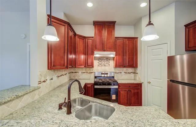 a kitchen with stainless steel appliances granite countertop a sink refrigerator and cabinets