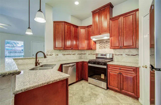 a kitchen with stainless steel appliances granite countertop wooden cabinets a sink and dishwasher