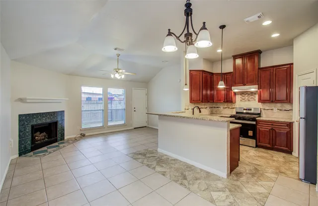 a kitchen with kitchen island granite countertop stainless steel appliances lots of counter top space cabinets and a fireplace