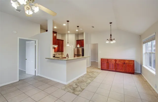 a large white kitchen with kitchen island a sink a counter space and stainless steel appliances