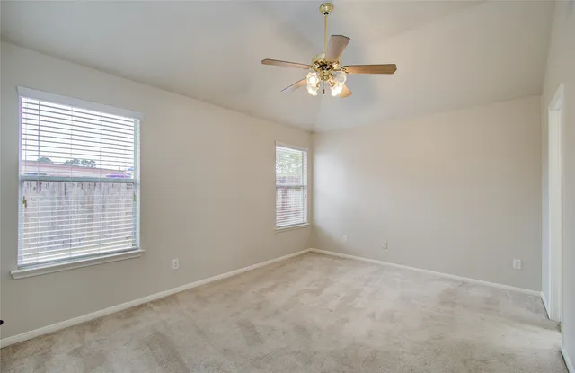 an empty room with windows and fan